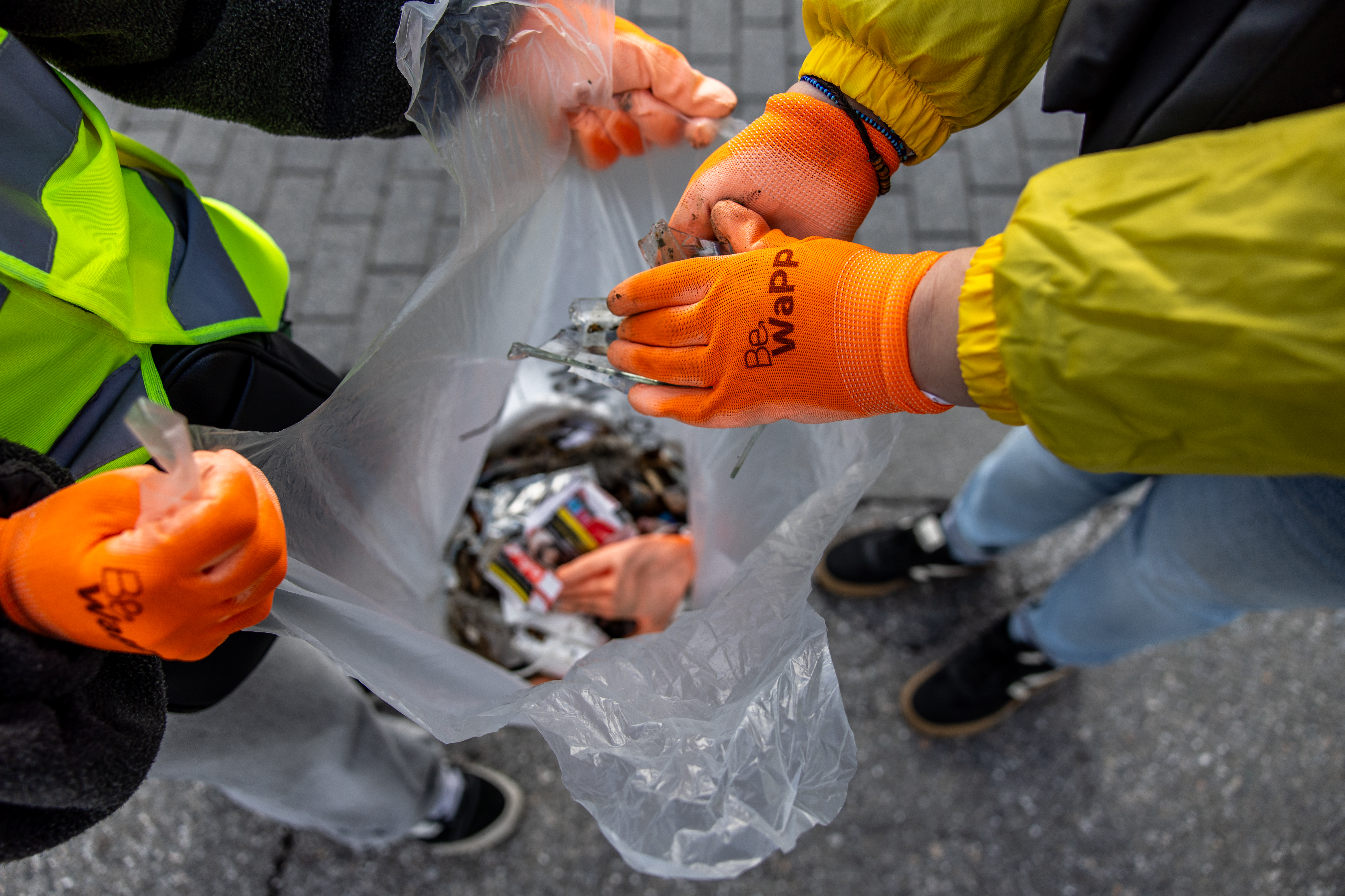 deux personnes remplissant un sac transparent avec des déchets